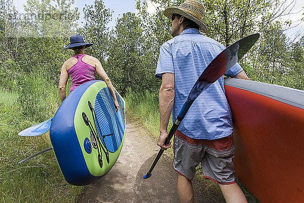 Ein junges Paar trägt Standup-Paddleboards zum Wasser in Oregon.