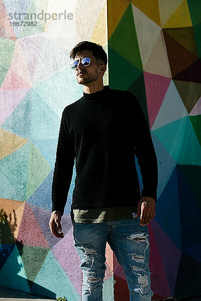Junge mit Sonnenbrille posiert vor einer bemalten Wand