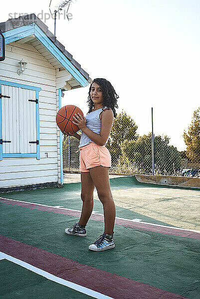Ein Mädchen steht auf einem Basketballplatz und posiert für eine Kamera