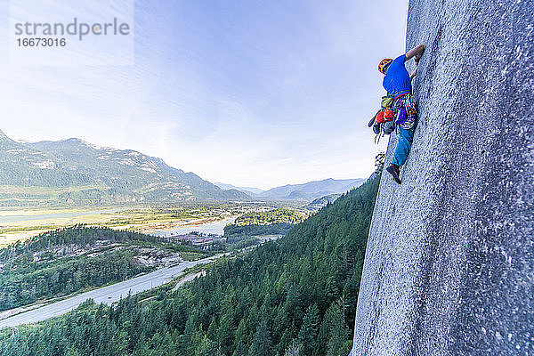 Mann beim Vorstieg auf Granit Squamish mit Blick auf das Tal im Hintergrund