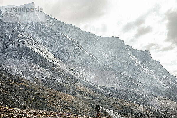 Backpacker ist ein Zwerg unter einem massiven Granitberg auf Baffin Island.