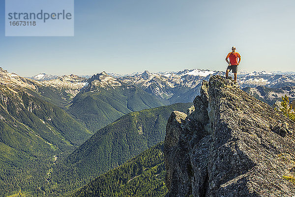 Bergsteiger steht auf dem Gipfel eines felsigen Berges  B.C. Kanada