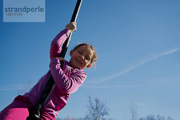 Mädchen auf einer Kinder-Seilrutsche mit blauem Himmel im Hintergrund