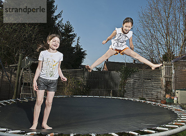 zwei junge Mädchen springen auf einem Trampolin in Woking - England