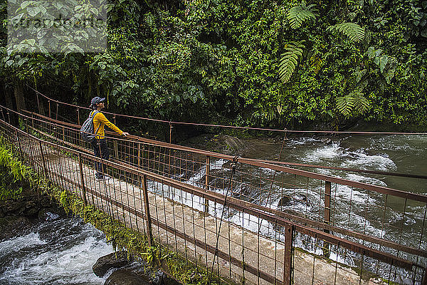 Frau beim Wandern über eine einfache Brücke im Regenwald in Mindo  Ecuador
