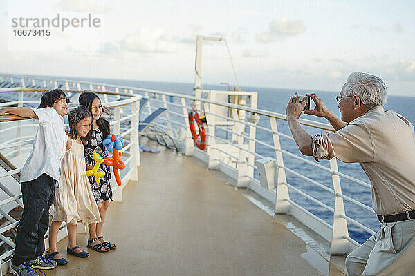 glückliche Kinder stehen auf einem Schiff und lächeln für Großvaters Kamera