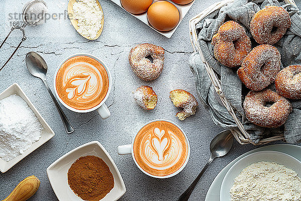 Kaffee mit Latte Art und kleinen Krapfen von Wein mit Zucker und Zimt und Zutaten. Donuts Dessert