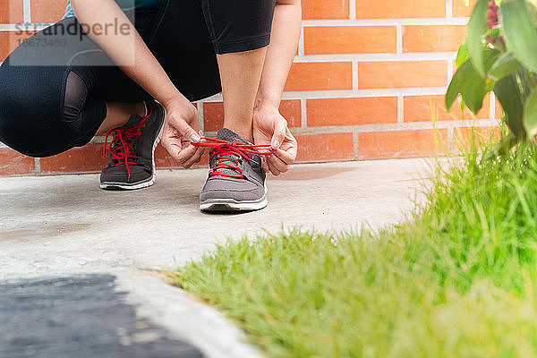 Sportlerin beim Binden der Schnürsenkel vor dem Laufen  Aktivitäten im Freien