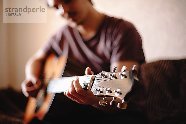 Junger Mann spielt Gitarre zu Hause