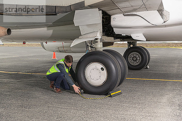 Männlicher Ingenieur beim Entfernen der Bremsen vom Flugzeugrad