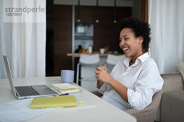 Glückliche gemischtrassige Geschäftsfrau während eines Online-Meetings