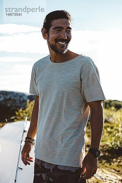 Mann schaut lächelnd weg an einem sonnigen Tag auf einem Campingplatz