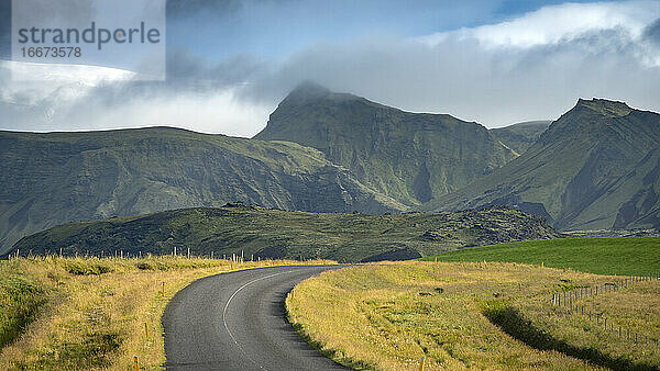 Leere Straße in Richtung Berge in Südisland gegen den Himmel