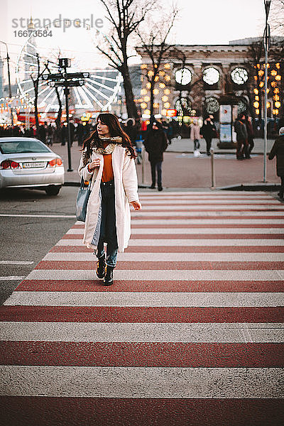 Nachdenkliches Teenager-Mädchen in warmer Kleidung beim Überqueren der Straße in der Stadt