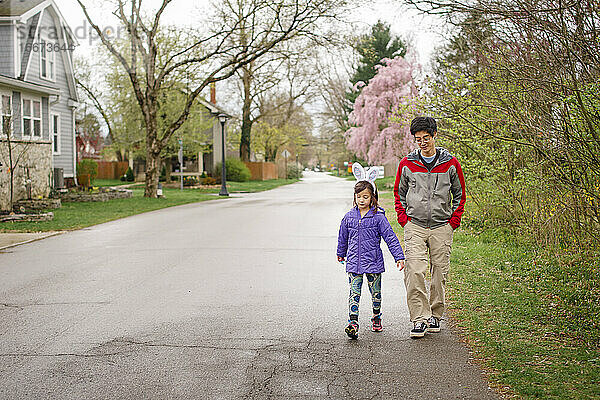 Ein Kind mit Hasenohren geht mit seinem Vater auf der Straße im Frühling spazieren