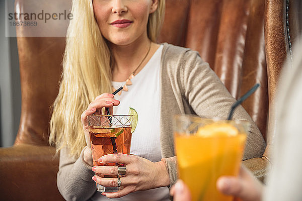 Crop Frau trinkt Cocktail mit Freund