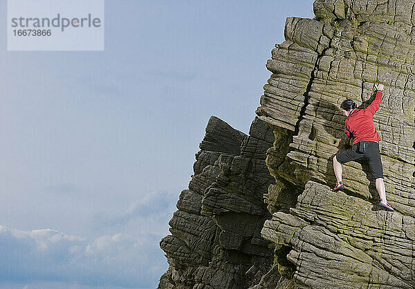 Frau beim Klettern an den Windgather-Felsen im britischen Peak District