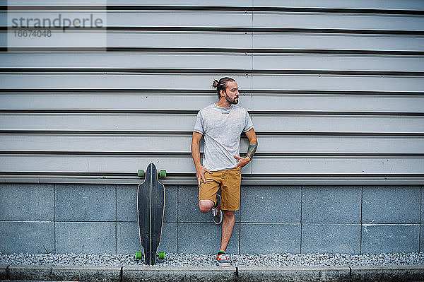 Junge posiert mit Skateboard in der Hand