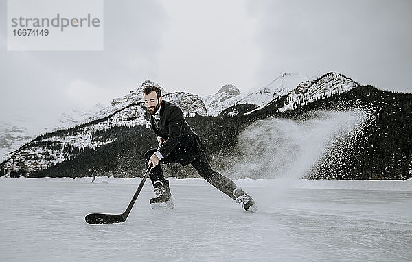 Eishockeyspieler im Anzug hält schnell an und schießt gefrorene Gischt auf den See