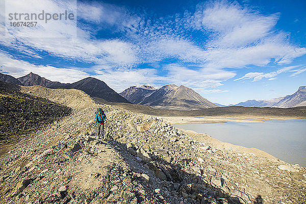 Rucksacktourist beim Wandern über eine felsige Gletschermoräne am Akshayak-Pass.