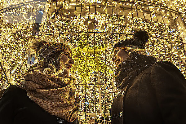 zwei junge Mädchen lachen im Hintergrund der Weihnachtsbeleuchtung