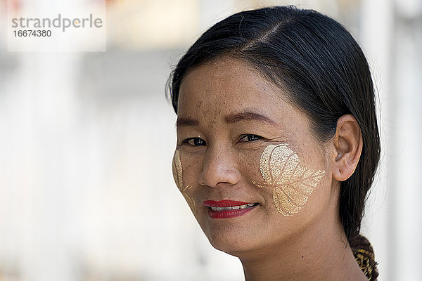 Porträt einer lächelnden Frau mit Thanaka-Malereien im Gesicht  Mandalay  Myanmar