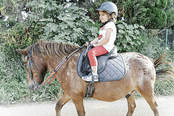 Glückliches Kind reitet Pferd auf der Koppel