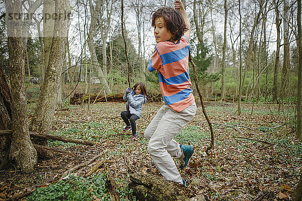 Ein Junge und ein Mädchen spielen an einem kühlen  grauen Tag gemeinsam im Wald Natur