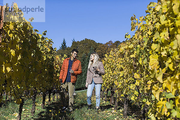 Ein junges Paar spaziert durch einen Weinberg auf einem Weingut in Oregon.