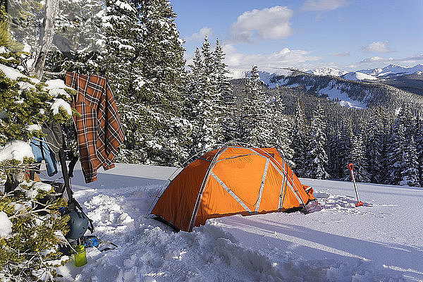 Orangefarbenes Zelt auf schneebedecktem Berg