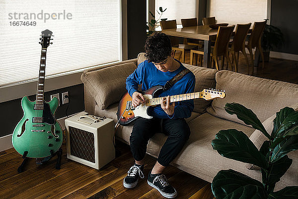 Junger Musiker im Teenageralter spielt zu Hause E-Gitarre