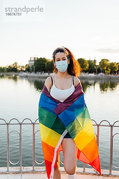 Junge Frau feiert Homosexuell Stolz Tag mit Maske und Regenbogen lgbt Flagge