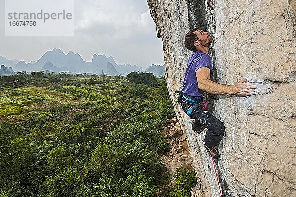 Mann beim Klettern auf dem Kalksteinfelsen Weißer Berg in Yangshuo