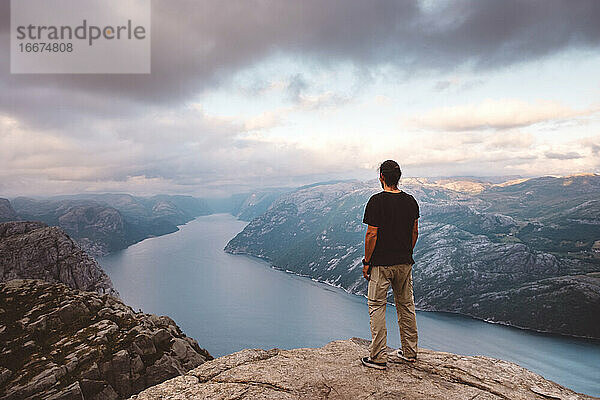 Mann steht am Rande einer Klippe am Preikestolen  Norwegen