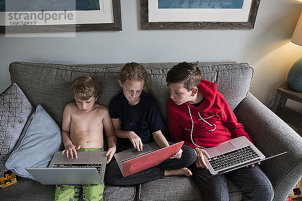Geschwister arbeiten zu Hause mit Laptops gemeinsam am Fernunterricht