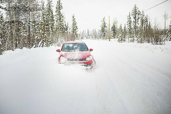 Vorderansicht eines roten Autos auf einer schneebedeckten Straße.