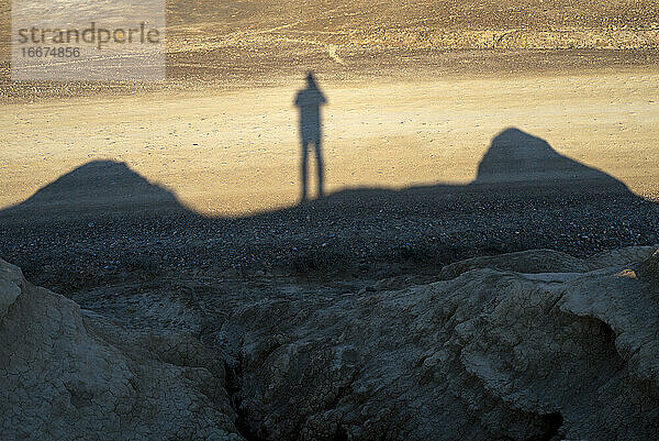 Mann Schatten über sonnigen Dünen in einer Wüste