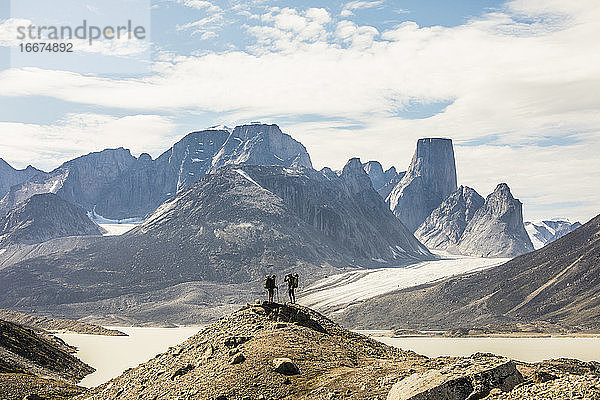 Zwei Rucksacktouristen stehen auf einem entfernten Bergrücken und betrachten die Aussicht.