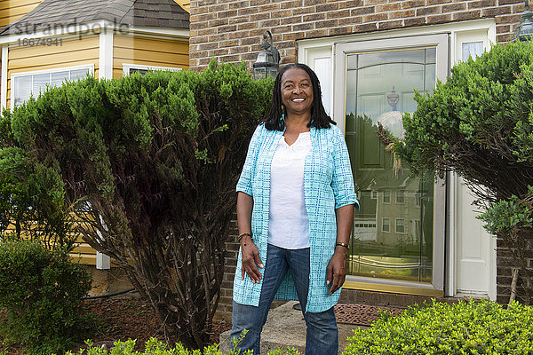 Lächelnde afro-amerikanische Frau vor ihrem Haus