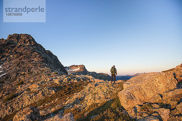 Rückansicht eines Rucksacktouristen  der eine Bergkette erkundet.