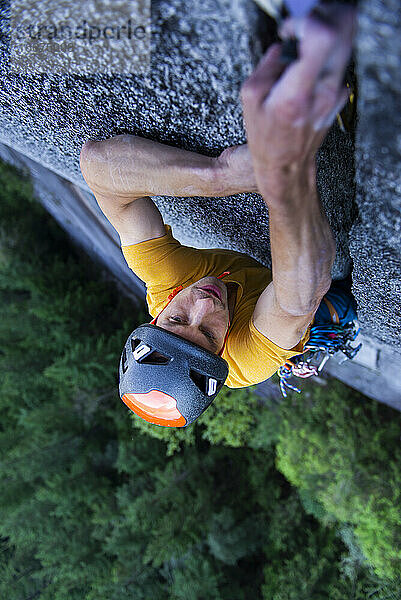 Mann platziert große Nocken in einem nicht ganz so breiten Granitriss beim Klettern in Squamish