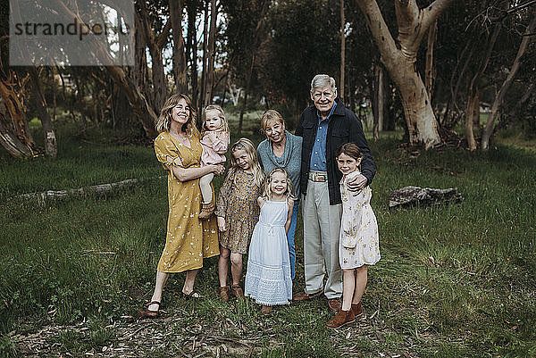 Porträt einer lächelnden und sich umarmenden Mehrgenerationenfamilie auf einem Feld