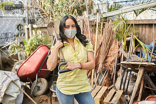Junge Frau mit einer Gesichtsmaske bei der Gartenarbeit
