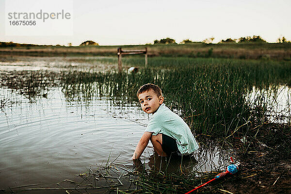 Junge sitzt im See und versucht  Fische zu fangen