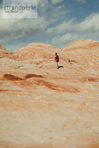 alleinstehende wanderin wandert auf eine versteinerte sanddüne in den roten felsen von utah