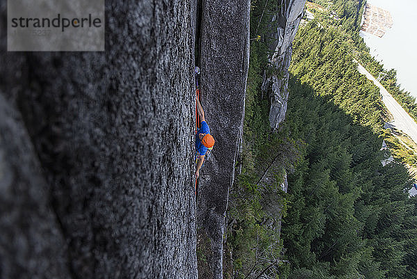 Ein Kletterer platziert eine Sicherung in einem breiten Riss hoch oben auf dem Chief in Squamish