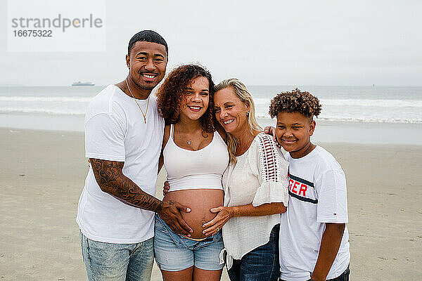 Familie posiert für Mutterschaftsfotos am Strand