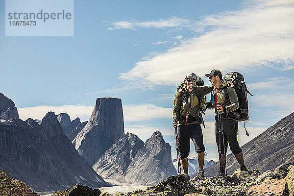 Zwei glückliche Rucksacktouristen lachen  während sie auf einem hohen Bergkamm mit Aussicht stehen.