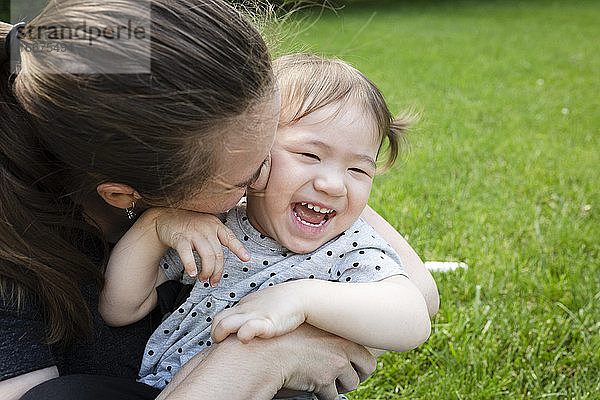 Glückliches Kleinkind Tochter lacht als Mutter kuschelt sie eng