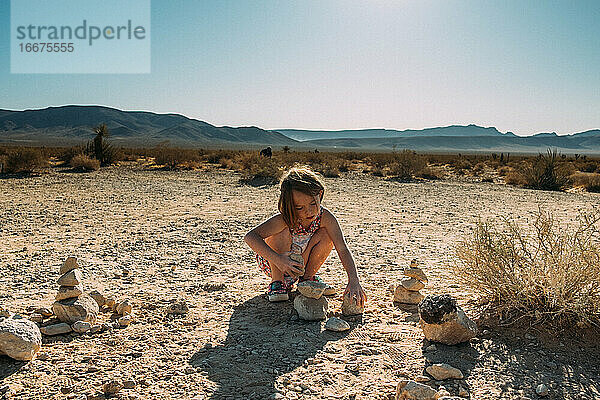 Junges Mädchen baut mit Steinen in der Wüste